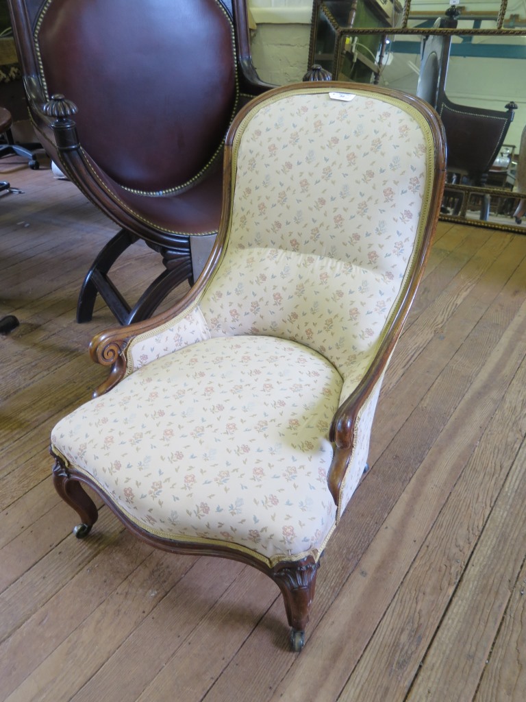 A mid Victorian walnut nursing chair, the upholstered hoop back over scrolled low arms on moulded