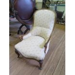 A mid Victorian walnut nursing chair, the upholstered hoop back over scrolled low arms on moulded