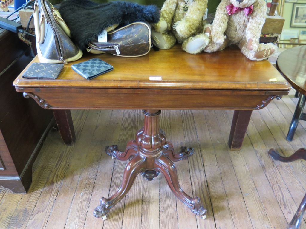 A mid Victorian mahogany foldover card table, the rectangular top enclosing a circular baize