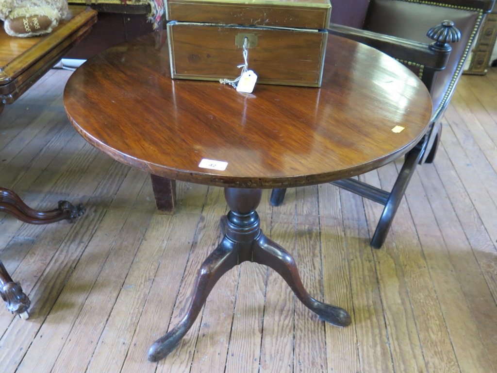 A George III mahogany snaptop tripod table, the circular top on a baluster stem and cabriole legs,