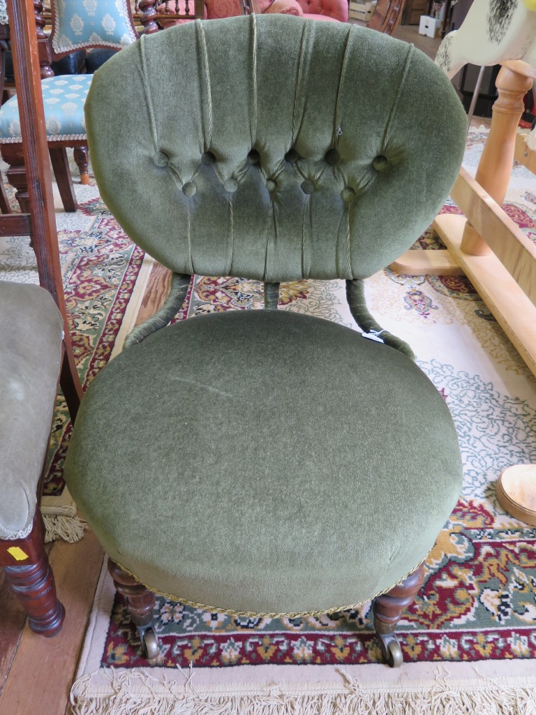 A late Victorian green upholstered fire side chair, the oval button back and seat on turned legs and