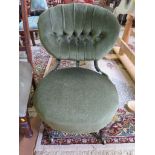 A late Victorian green upholstered fire side chair, the oval button back and seat on turned legs and