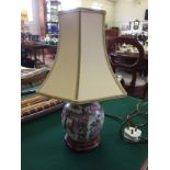 A small table lamp with a porcelain decorated base in the fami rose style complete with shade
