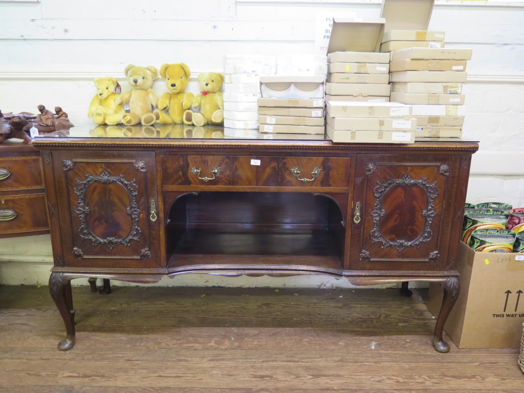 A 1920s mahogany sideboard by Maple & Co, the central drawer and open shelf flanked by foliate