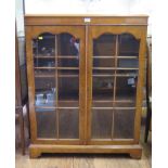 A burr walnut bookcase with twin glazed doors on bracket feet, 87cm wide