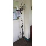 A wrought iron adjustable standard lamp, with converted oil lamp reservoir on a tripod base