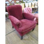 A late Victorian red upholstered armchair on ring turned tapering legs and pot castors