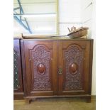 A late Victorian walnut side cabinet with a pair of ornately scroll carved and cabochon doors on