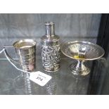 A small silver pedestal dish, a silver scent bottle lid and a plated measuring cup