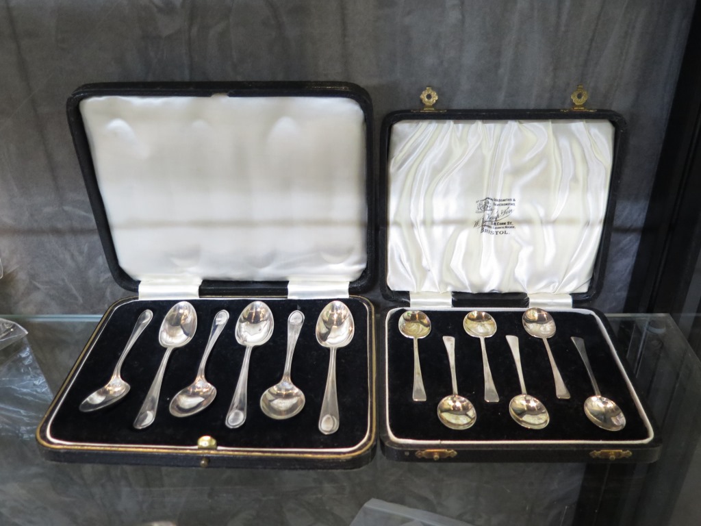 A cased set of silver tea spoons together with a cased set of silver coffee spoons