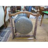 A brass dinner gong 46cm diameter in a tapering bobbin turned frame