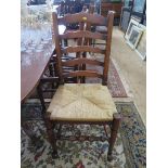 A set of six oak ladderback chairs with rush seats on turned tapering legs joined by stretchers