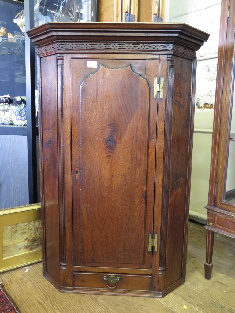 A George III mahogany corner cabinet, the moulded cornice with blind fret carved frieze over