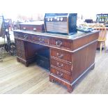 A reproduction mahogany desk, the leather top over three frieze drawers on pedestals each with three