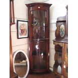 A 1930s mahogany corner cabinet, the dentil cavetto moulded cornice over a long glazed door on