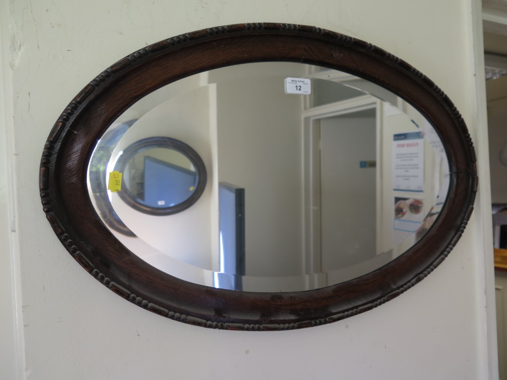 An oval oak framed mirror 67cm wide and another oval mirror 59cm wide