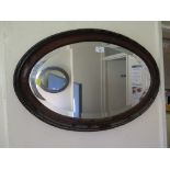An oval oak framed mirror 67cm wide and another oval mirror 59cm wide