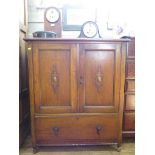 A 1930s oak cabinet, the twin panelled and cabochon applied doors over a long drawer on turned feet,