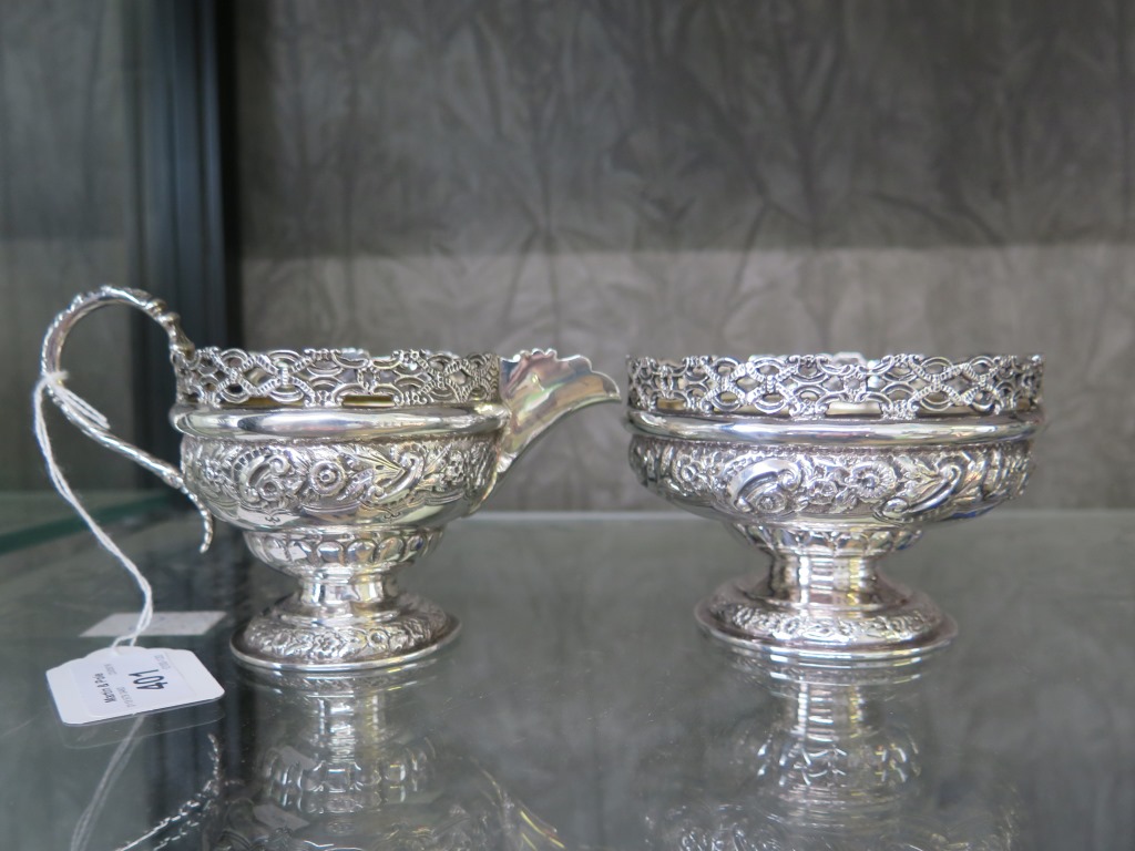 A silver cream jug decorated in relief with pierced gallery and a matching sugar bowl, London 1895