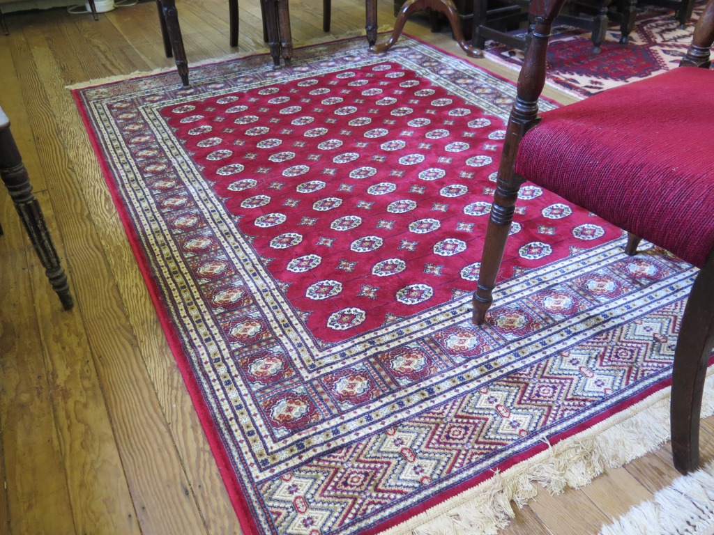 A Kashmir Bokhara style rug, the rows of guls on a red field within a multiple border 244cm x 155cm