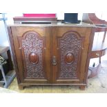 A late Victorian walnut side cabinet with a pair of ornately scroll carved and cabochon doors on