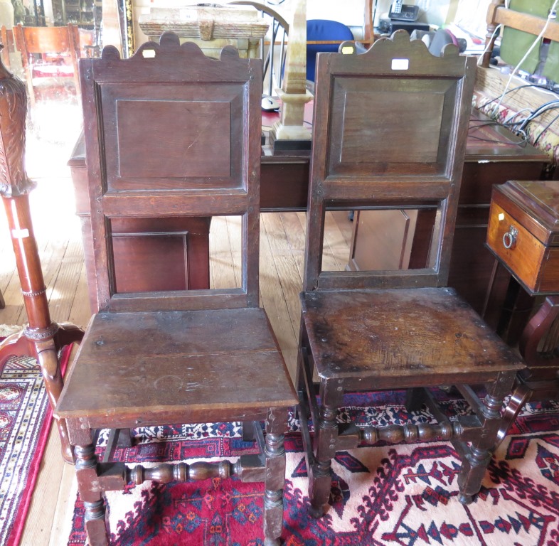 A pair of late 17th century oak back stools, circa 1680, the shaped top rails over panelled backs