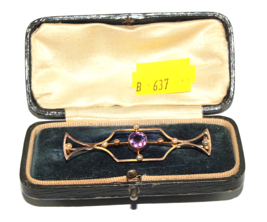 A gold brooch set with seed pearls and central amethyst