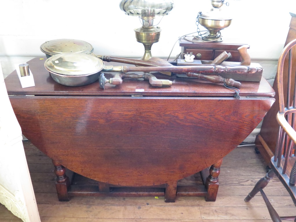 An 18th century style oak gateleg table, the oval top over a frieze drawer on turned and block