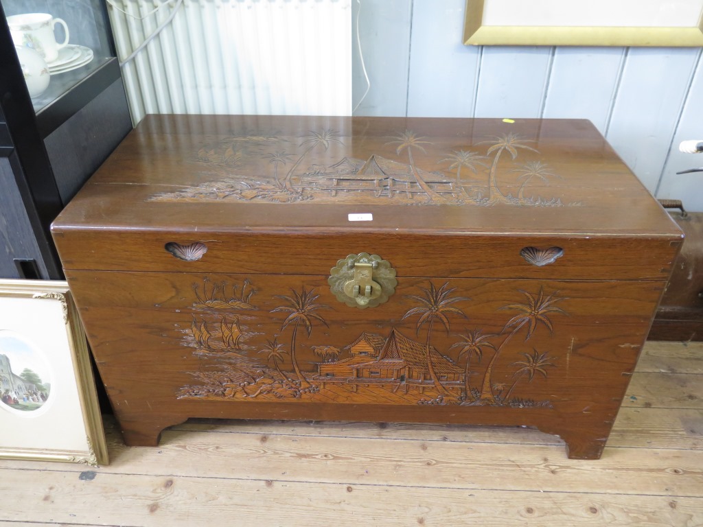 A Far Eastern camphorwood chest, carved with tree and houses 101cm wide, 50cm deep, 55cm high