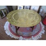 A large Moroccan brass top table, the circular top with geometric design over a turned and block