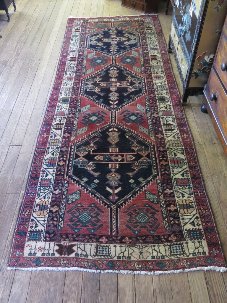 A Persian runner with three dark medallions on a red field with multiple border 316cm x 117cm