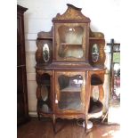 A late 19th century French inlaid mahogany display cabinet, the shaped pediment over a glazed