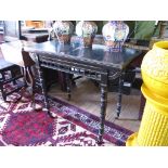 A Victorian ebonised foldover card table in the Aesthetic style with gilt highlights, the spindle