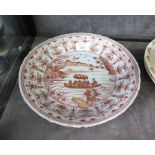 An 18th century Chinese red and gilded shallow dish depicting a boat on a lake within a floral