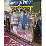 An ebonised and giltwood over mantel mirror, the arched bevelled plate with a beaded frame