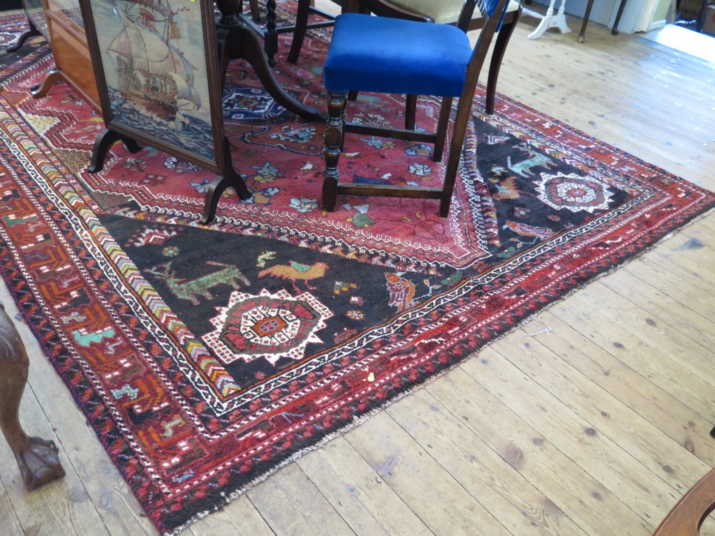 A Persian Kashqai design carpet with red field and blue spandrels filled with stylised birds and