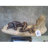 A figure of an Aboriginal man sleeping on driftwood, c.1920, 34cm wide