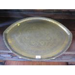 A Middle Eastern brass tray, biconvex with scroll and star design 69cm x 54cm