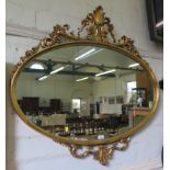 An oval giltwood framed wall mirror, with foliate acanthus carved crest 99cm x 104cm