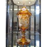 A Victorian amber glass goblet and cover, etched with birds among berries, on a facetted pedestal