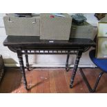 A Victorian ebonised foldover card table in the Aesthetic style with gilt highlights, the spindle