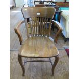 A 1930s oak office chair, the rail back over a moulded seat on cabriole legs joined by stretchers