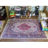 A Kashmir design rug, the red medallion on an ivory field filled with flowers and birds, within blue