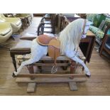 A small grey rocking horse, Ayres type, lacking horsehair tail, on a trestle base, 96cm high 110cm