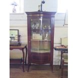 An Edwardian mahogany and satinwood crossbanded serpentine display cabinet, the raised back over a