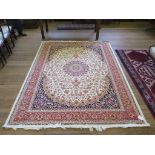 A Kashmir design rug, the red medallion on an ivory field filled with flowers and birds, within blue