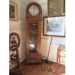 A 1930s oak longcase clock, the arched case enclosing a silvered dial above a glazed trunk and lobed