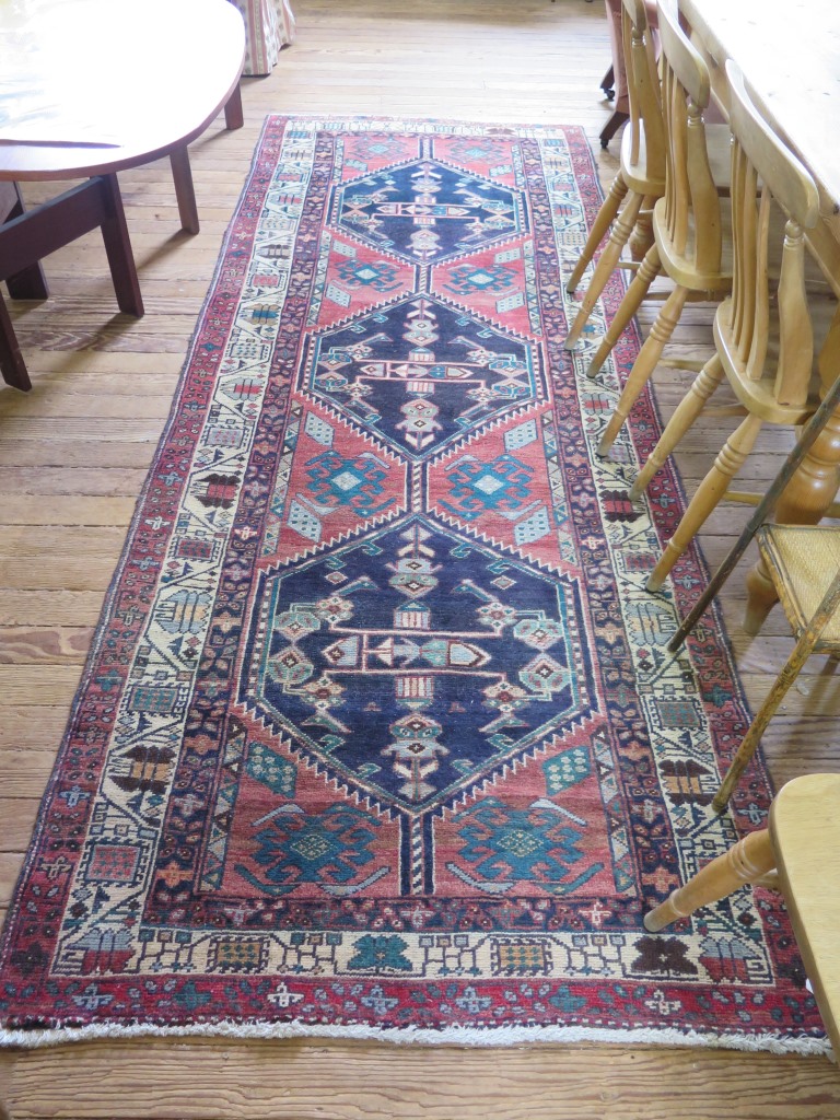 A Persian runner with three dark medallions on a red field with multiple border 316cm x 117cm