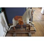 A small grey rocking horse, Ayres type, lacking horsehair tail, on a trestle base, 96cm high 110cm