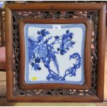 A Chinese blue and white plaque, depicting an exotic bird in flowering branches in a hardwood carved